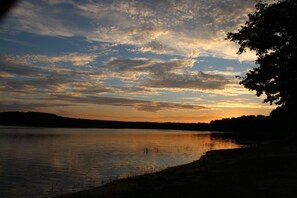 A calm lake at sunset with a silhouette of trees on the right and a cloudy sky. - Ecolodge Beauregard (Treigny-Perreuse-Sainte-Colombe)