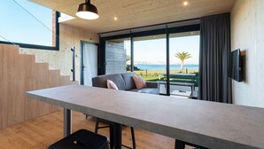 Une cuisine moderne dotée d’un grand îlot central, d’un plafond en bois et offrant une vue sur la mer.