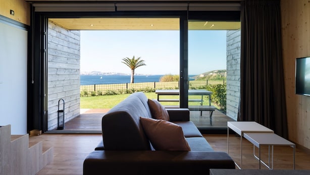 Un salon moderne doté d’une grande porte-fenêtre coulissante donnant sur un balcon avec vue sur la mer.