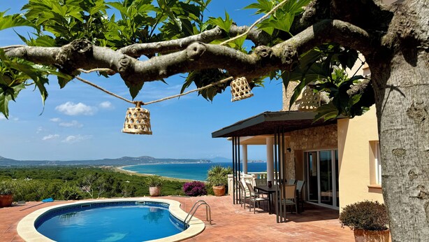 A private pool area with a view of the sea, outdoor seating, and potted plants.