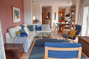 A living room with a sofa, armchairs, a coffee table, and a dining area with a table and chairs. - Villa with splendid sea view, 500 m. from the beach, Wifi, pool (Begur)