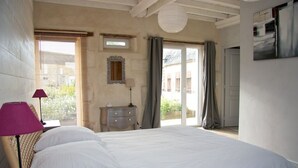 Een slaapkamer met een groot bed, een nachtkastje, een lamp, een spiegel en uitzicht buiten door een schuifdeur.