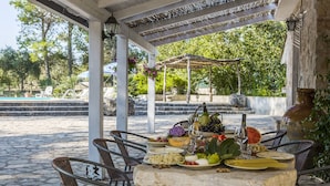 Un espace de restauration en plein air doté d’un sol en pierre, de chaises en osier et d’une table dressée avec différents plats et boissons.