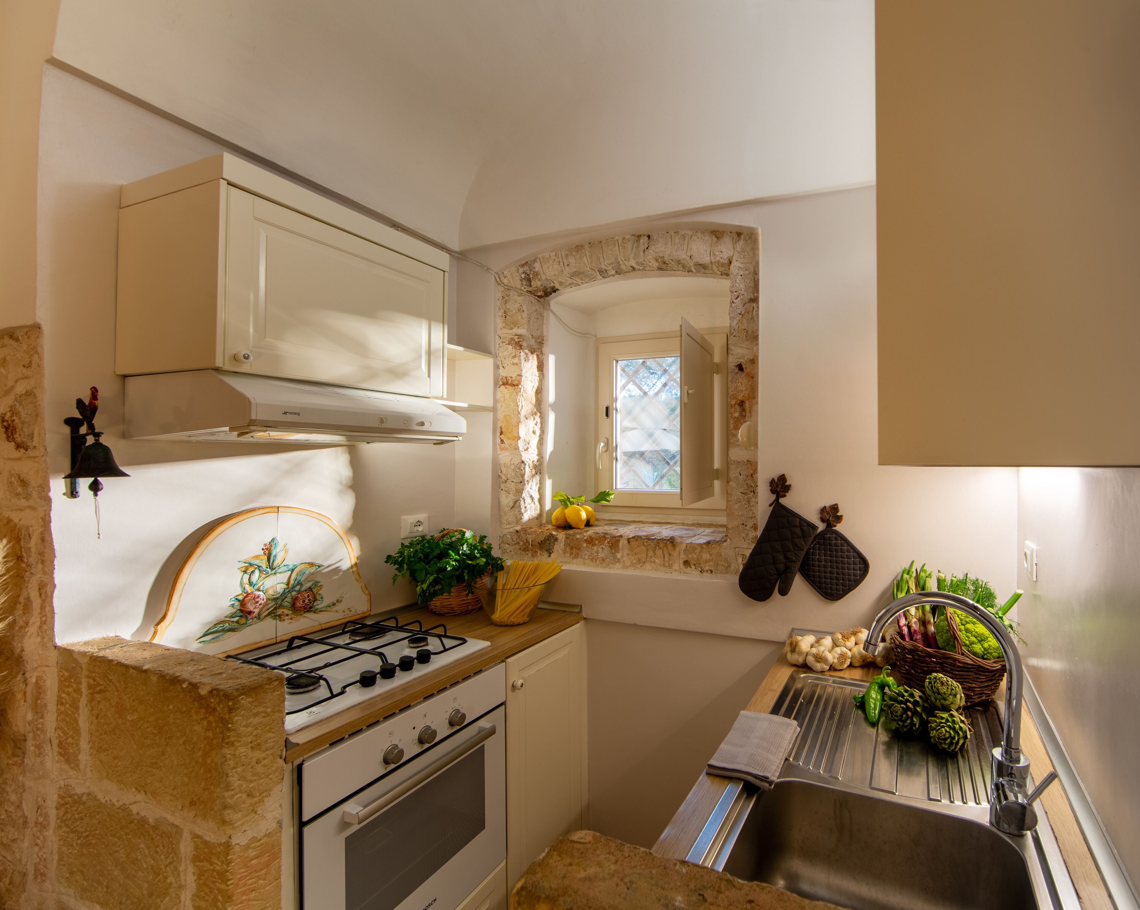 A compact kitchen with a gas stove, oven, and a small window.