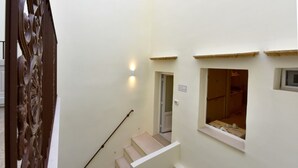 Una escalera que conduce a un segundo piso con un pequeño ventanal y una puerta que dice 'Salle de Confort'.