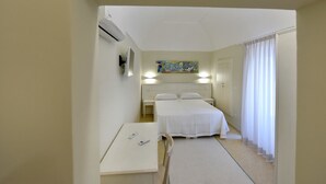 Una habitación de hotel con cama, mesitas de noche, un escritorio y un cuadro en la pared.