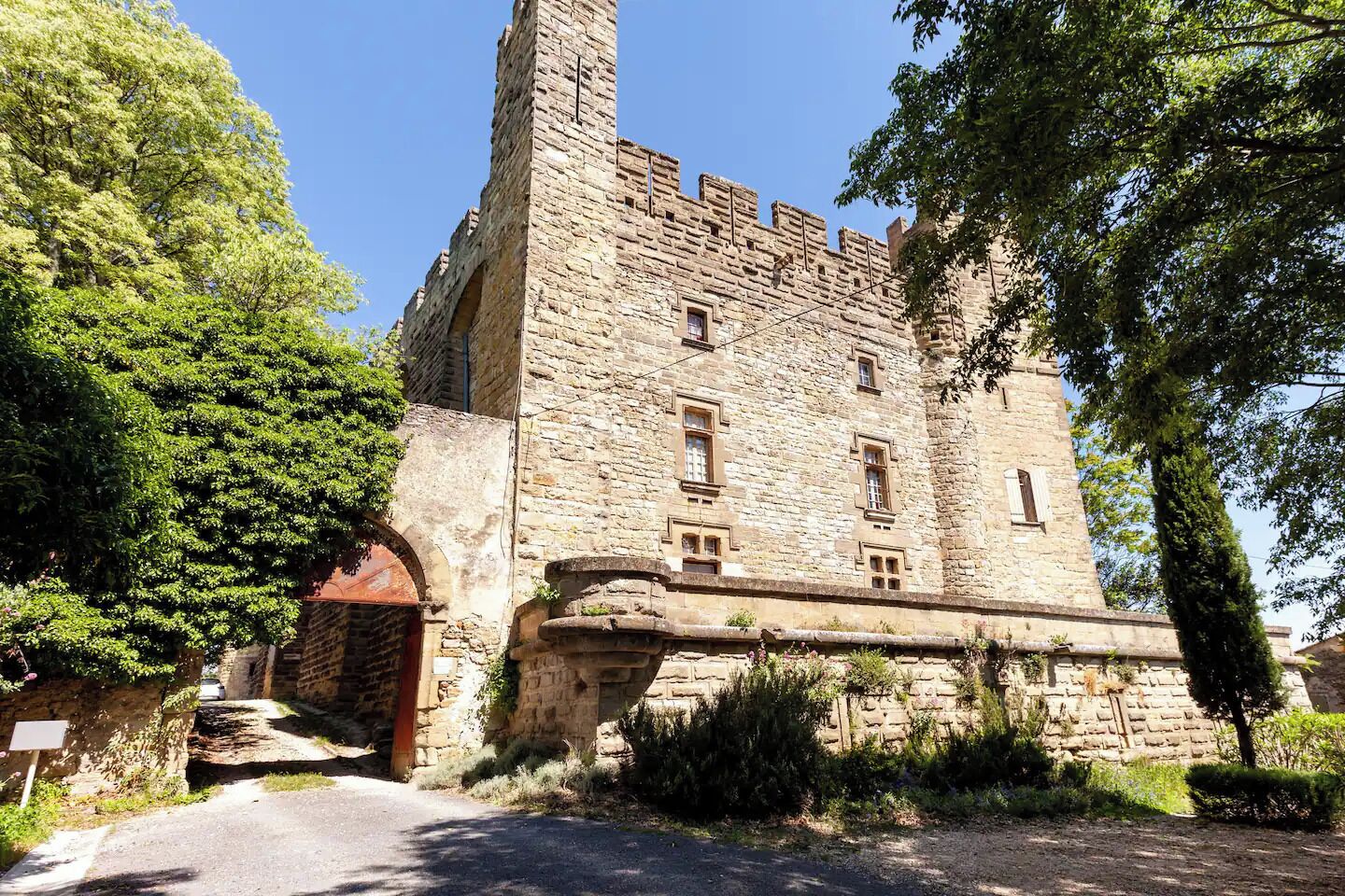 Un bâtiment historique en pierre, doté d’une tour imposante, d’une entrée en arc de cercle et de nombreuses fenêtres.