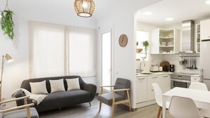 Eine moderne Wohnung mit einem grauen Sofa, einem Esstisch und einer Küchenzeile.