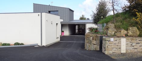 A modern building with a flat roof, a gated entrance, and a stone wall with a sign.
