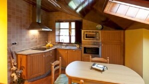 A compact kitchen with wooden cabinets, a microwave, and a sink. - Rural Apartment Casa El Llombo, ideal to disconnect, surrounded by nature. (Franco (El))
