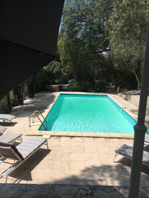 A rectangular swimming pool with clear water, surrounded by tiled flooring and shaded by trees. - Cabanon provençale (La Seyne-Sur-Mer)