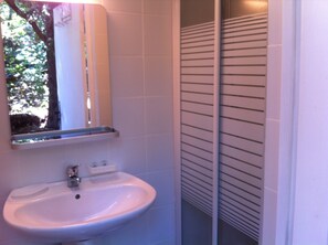 A bathroom with a white sink, a mirror, and a window with a view of trees. - Cabanon provençale (La Seyne-Sur-Mer)