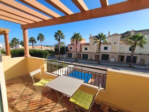 A balcony with a pool, yellow chairs, and a view of buildings and palm trees. - DomusIberica Burgau, 2 bedroom house with A/C, private pool, walk to the beach! (Burgau)
