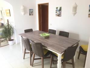 A dining area with a rectangular table, six chairs, and a potted plant.