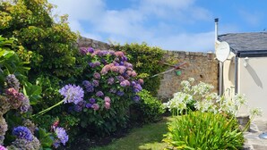 A garden with hydrangeas and white flowers, a stone wall, and a building with a chimney. - House / Villa - Plogoff (Plogoff)