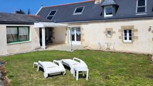 A house with a covered patio, a lawn, and two white lounge chairs. - House / Villa - Plogoff (Plogoff)