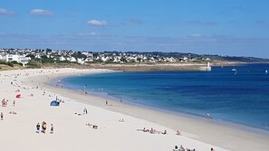 A wide sandy beach with clear blue water, a lighthouse in the distance, and a row of white houses along the shore. - House / Villa - Plogoff (Plogoff)