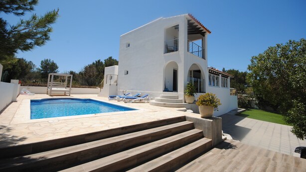 Una casa moderna de dos pisos con piscina, mobiliario exterior y un jardín cuidado.