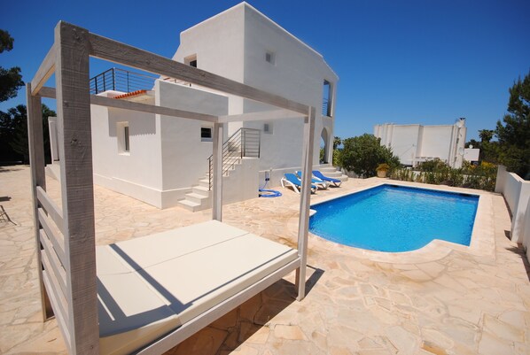 A modern villa with a stone pool, a wooden pergola, and a white exterior. - Modern Ibiza Villa with Private Pool – Close to the Beach & San Antonio Bay (Ibiza)