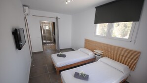 Habitación de hotel con dos camas, un televisor y una ventana con vistas.
