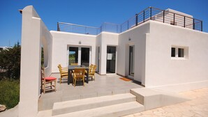 Una casa moderna con patio, mobiliario exterior y balcón.