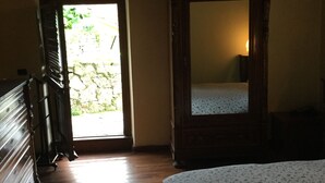 A bedroom with a wooden dresser, a large mirror, and a bed with a floral bedspread. - mansion - Riccò del Golfo (Riccò del Golfo)