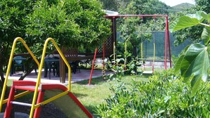 A playground with a red and yellow slide, surrounded by lush greenery and trees. - Casa Vacanze Donna Antonia (Centola)