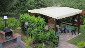 A patio area with a covered table, outdoor seating, and a brick barbecue grill. - Casa Vacanze Donna Antonia (Centola)
