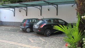 A parking area with two cars parked under a green awning. - Casa Vacanze Donna Antonia (Centola)
