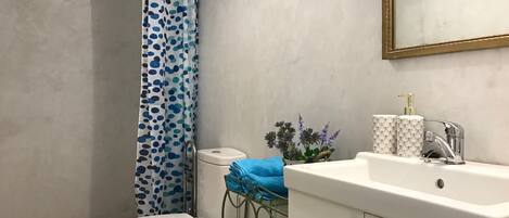 Een badkamer met toilet, wastafel, spiegel en douchegordijn.