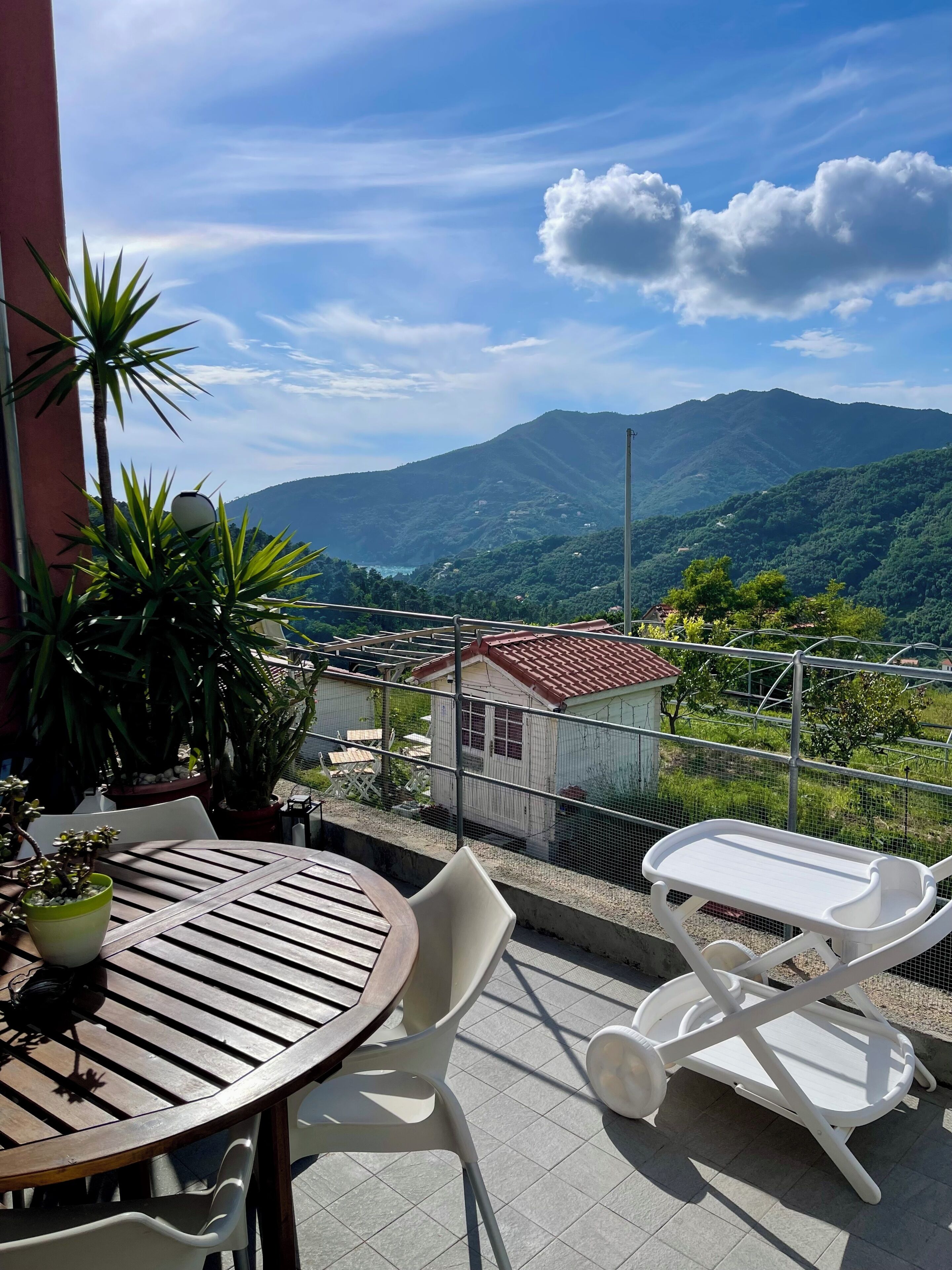 Un balcón con mesa y sillas, con vistas a un paisaje montañoso.