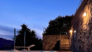 Ein Schwimmbecken mit klarem Wasser, umgeben von einer Steinmauer und einer Holzterrasse.