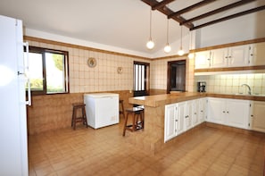 Compact kitchen with central island, cabinetry, and tiled backsplash, featuring a refrigerator, sink, and coffee maker.