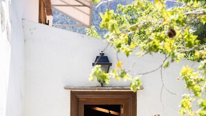 A rustic wooden door with a small window, surrounded by potted plants and baskets, set against a white wall. - El Nogal House, La Orotava (La Orotava)