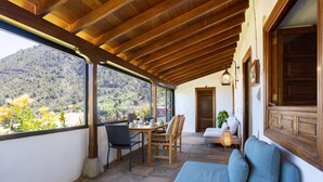 A covered patio with a wooden ceiling, a dining table with chairs, a blue sofa, and a view of a mountainous landscape. - El Nogal House, La Orotava (La Orotava)
