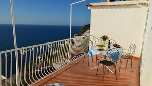 A balcony with a table set for two, overlooking the sea.