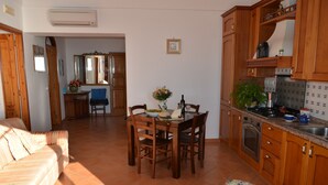 A cozy living room with a sofa, a dining table with chairs, and a kitchen area with wooden cabinets and a stove.