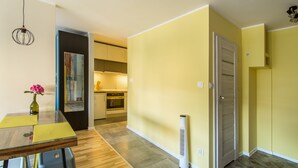 A modern kitchen with a built-in oven and a dining area with a wooden table and chairs. - Locum Magdalena Wroclaw Market (Wroclaw)