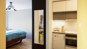 A compact room with a bed, a kitchenette, and a mirror reflecting a dining area. - Locum Magdalena Wroclaw Market (Wroclaw)