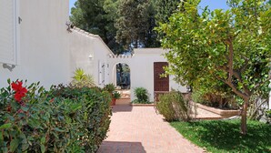 A paved pathway leading to a building with a white exterior and a brown door. - Lovely 3 bedroom villa with private pool and lovely views (Almuñecar)