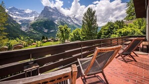 A terrace with wooden railings, a brick floor, and two reclining chairs. - Cozy free standing Chalet with garden and amazing mountain views (Grindelwald)