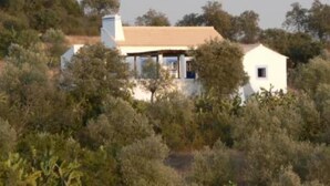 Un bâtiment blanc, doté d’un toit en pente, entouré d’une végétation luxuriante.