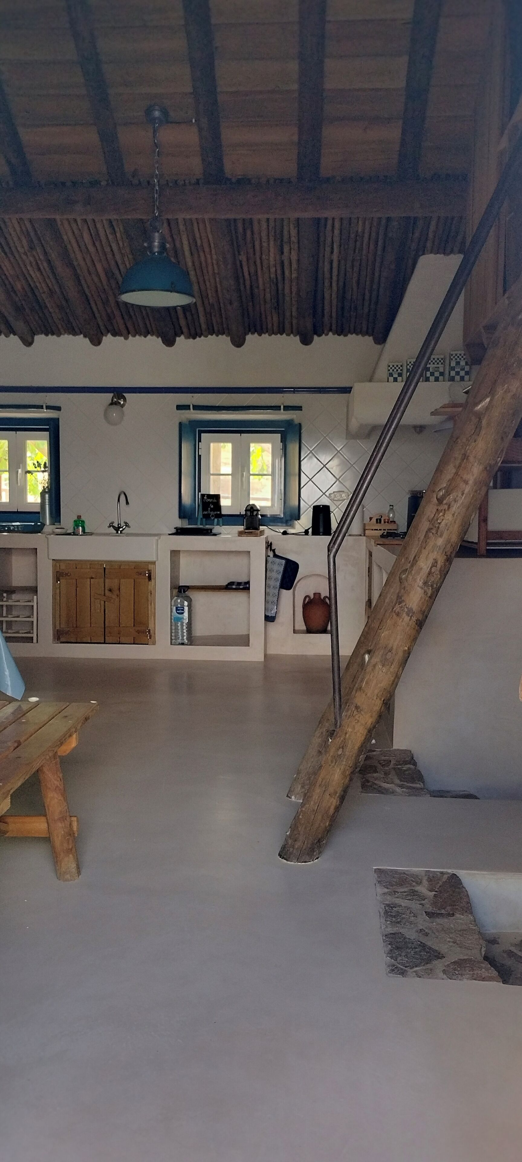 Un interior espacioso con techo de madera, una zona de cocina y una escalera.