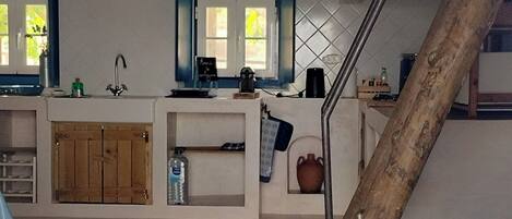 Un interior espacioso con techo de madera, una zona de cocina y una escalera.