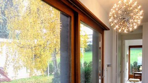 Un pasillo con ventanas amplias, suelo de madera y una lámpara moderna.