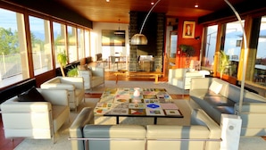 Amplia sala de estar con una mesa de centro, asientos cómodos y ventanas grandes que ofrecen vistas al exterior.
