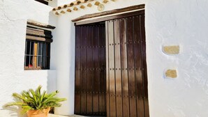 A white building with a large wooden door and a window with bars.