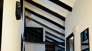 A narrow hallway with a tiled floor, a wooden bench, and a bookshelf with books.