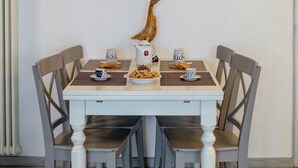 Une table à manger avec quatre chaises, une branche d’arbre servant de décoration murale et des tableaux encadrés.