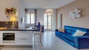 Une cuisine moderne avec un coin repas, un canapé bleu et un élément décoratif mural.